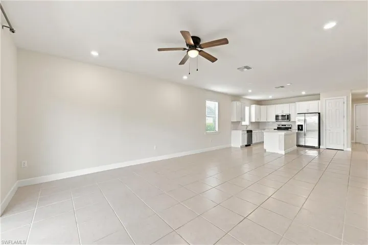 Spacious open-concept living area with tile flooring throughout, recessed lighting, and ceiling fan