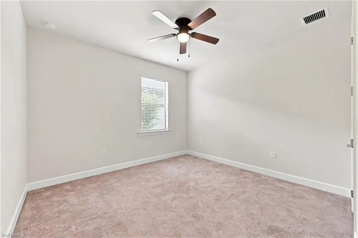 Carpeted room featuring a ceiling fan with integrated lighting, a window with blinds, and white trim