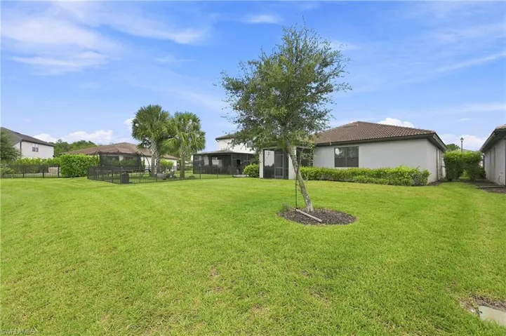 Expansive manicured lawn with mature landscaping and established trees, complemented by multiple single-story residences with neutral exterior finishes and pitched rooflines positioned throughout the property grounds
