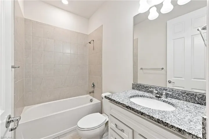 Spa-inspired bathroom featuring a white vanity with ample storage, speckled stone countertop, and an undermount sink