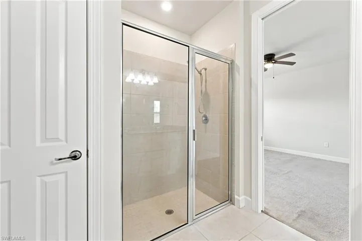 Walk-in shower with clear glass enclosure, tiled walls, and a built-in bench