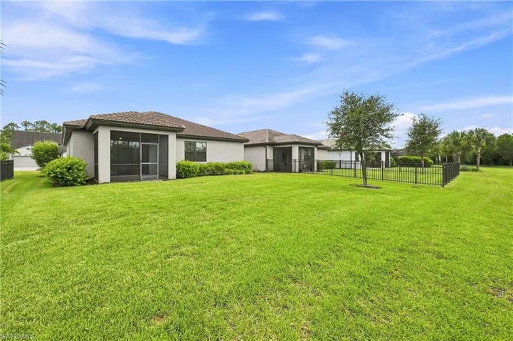 Expansive manicured lawn with mature landscaping and black perimeter fencing