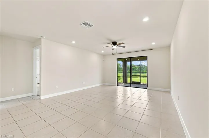 Expansive room featuring tile flooring, a dark-toned ceiling fan, recessed lighting, and sliding glass doors leading to a screened outdoor area