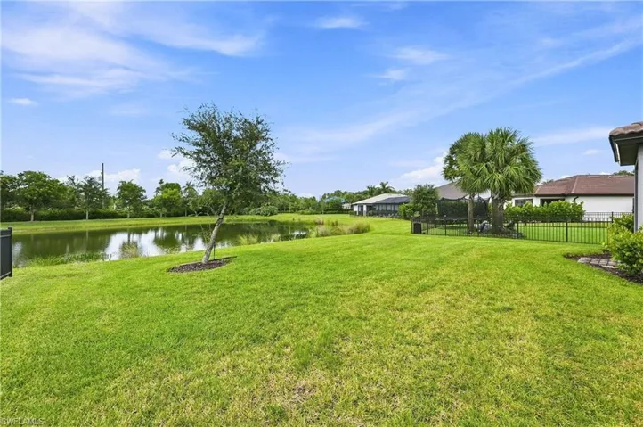 Expansive rear yard featuring a large lawn area, mature landscaping, and a water feature