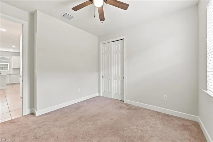 Neutral wall paint, ceiling fan, and carpeted flooring
