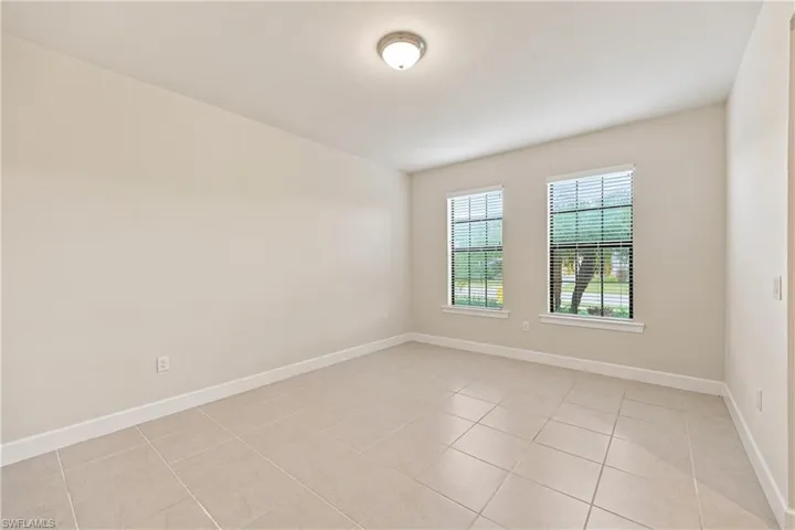 Bright, airy room featuring dual casement windows with gridded panes, neutral wall finishes, and neutral tile flooring