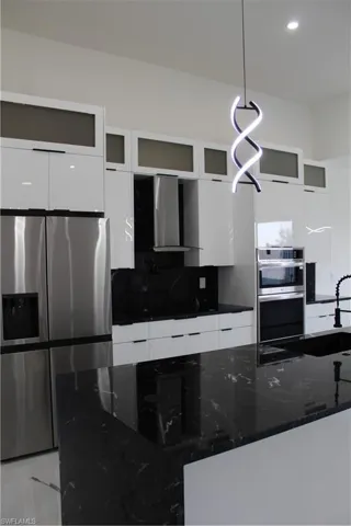 Kitchen with modern cabinets, refrigerator, white cabinets, range hood, and decorative backsplash