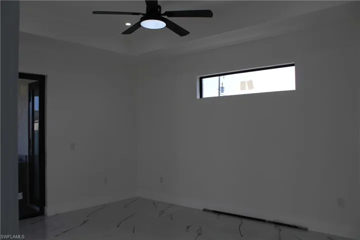 Empty room with baseboards, light marble finish floors, and a ceiling fan