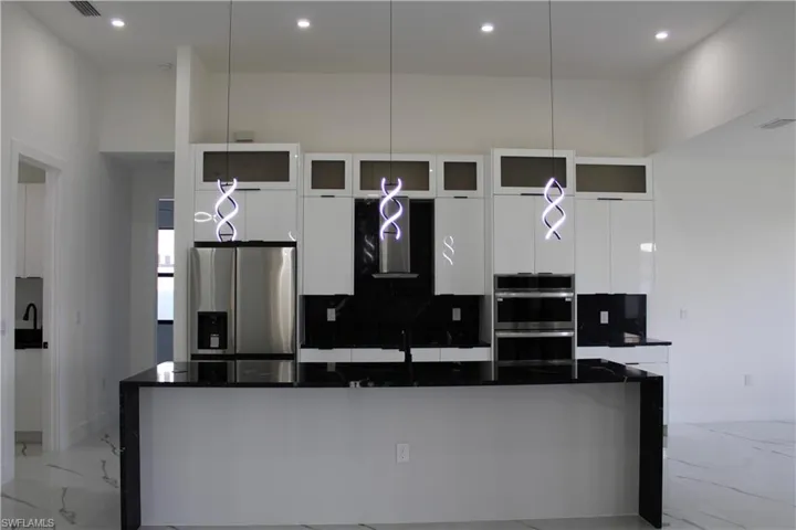 Kitchen featuring stainless steel appliances, modern cabinets, white cabinetry, and recessed lighting