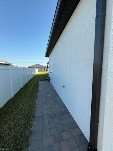 View of side of property with a yard, a patio area, stucco siding, and fence