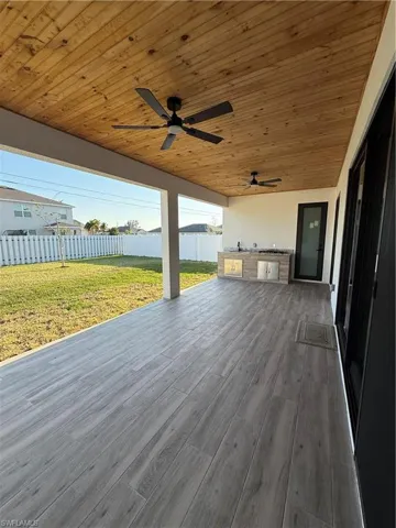 Deck with area for grilling, a yard, ceiling fan, and fence