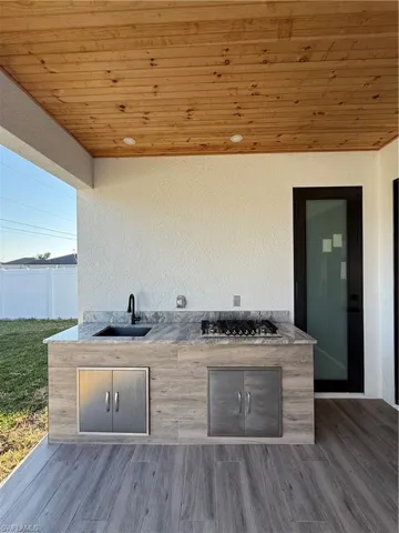 View of patio / terrace with a sink, fence, and an outdoor kitchen