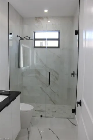 Bathroom featuring vanity, a marble finish shower, toilet, marble finish floors, and recessed lighting