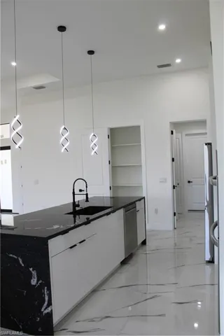 Kitchen featuring a sink, modern cabinets, light marble finish flooring, white cabinets, and recessed lighting