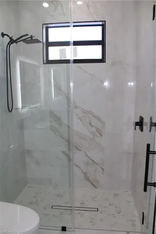 Bathroom featuring a marble finish shower and toilet