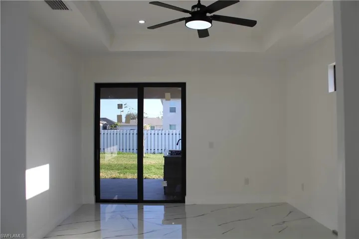Spare room with a raised ceiling, baseboards, light marble finish floors, ceiling fan, and recessed lighting