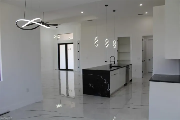 Kitchen with a sink, a towering ceiling, baseboards, light marble finish floors, and recessed lighting
