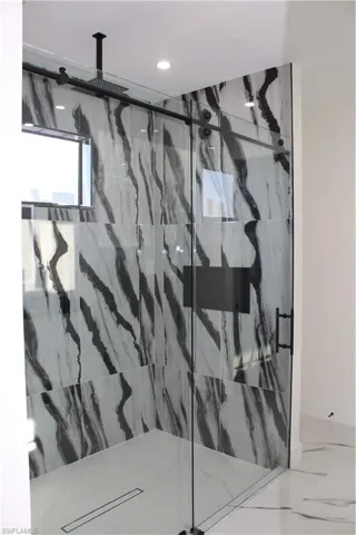 Bathroom with a marble finish shower, marble finish flooring, recessed lighting, and baseboards