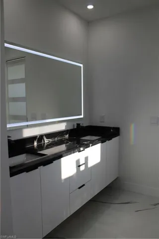 Bathroom featuring vanity, baseboards, and recessed lighting