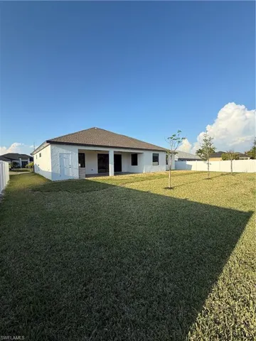 Rear view of property featuring fence and a lawn