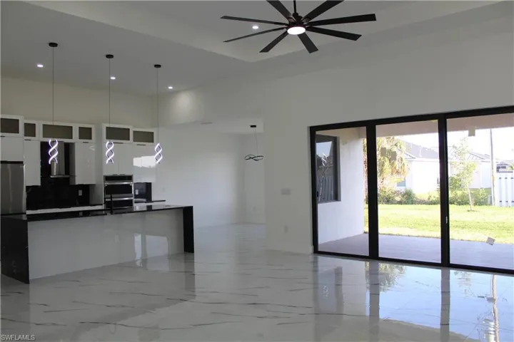 Kitchen with dark countertops, modern cabinets, a towering ceiling, white cabinets, and a ceiling fan