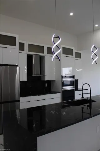 Kitchen featuring modern cabinets, ventilation hood, white cabinets, fridge, and recessed lighting