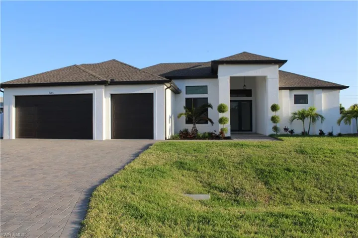 Prairie-style house featuring an attached garage, decorative driveway, a front lawn, and stucco siding