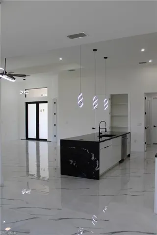 Kitchen with modern cabinets, a sink, dark countertops, light marble finish floors, and recessed lighting