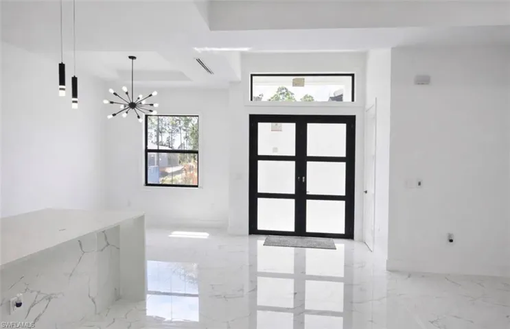 Foyer featuring a modern black framed double door entry with opaque glass panels, transom window, and adjacent window
