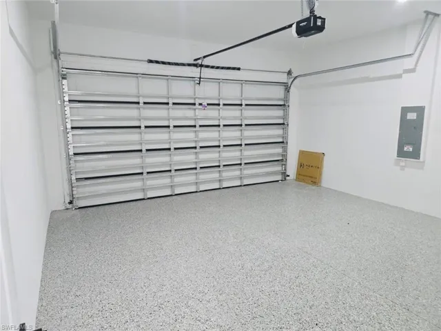 Attached garage featuring a durable speckled epoxy floor finish, a modern sectional garage door with automatic opener, and crisp white painted walls