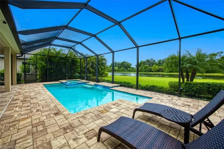 View of swimming pool featuring glass enclosure, an in ground hot tub, and a patio area