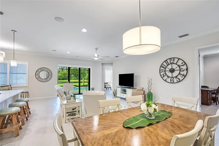 Tiled dining room with ceiling fan and ornamental molding