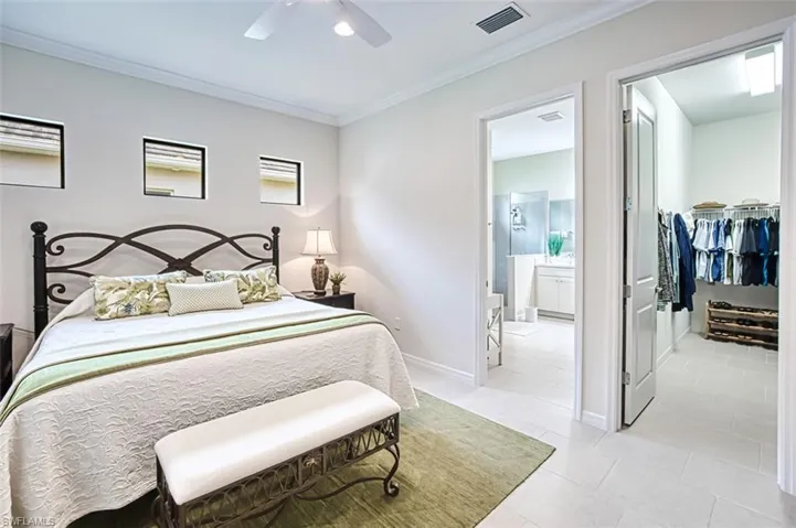 Bedroom featuring ceiling fan, ensuite bath, crown molding, and light tile patterned floors