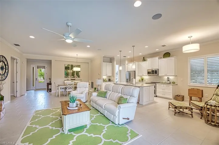 Tiled living room with ceiling fan and crown molding