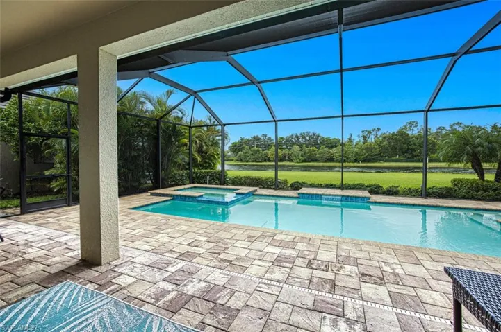 View of pool featuring glass enclosure, an in ground hot tub, and a patio area