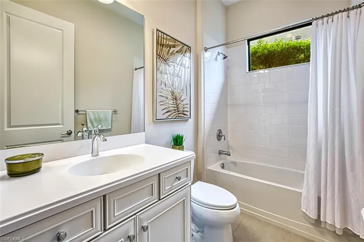 Full bathroom with tile patterned flooring, toilet, shower / tub combo with curtain, and vanity