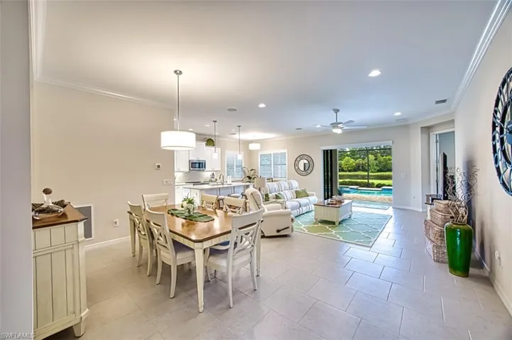Tiled dining area with ceiling fan and crown molding