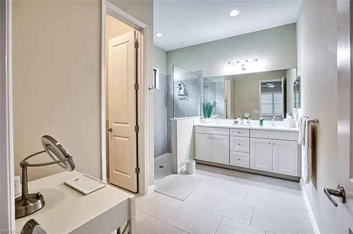 Bathroom featuring tile patterned flooring, a tile shower, and vanity