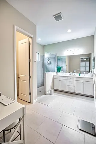 Bathroom featuring tile patterned floors, vanity, and tiled shower