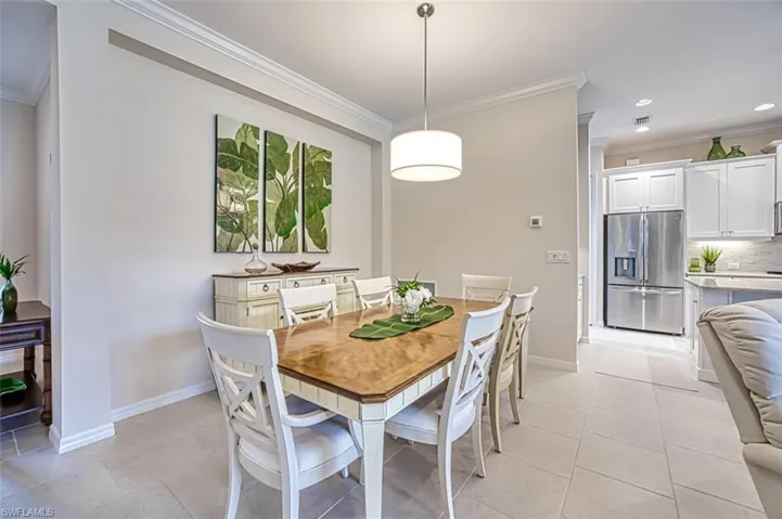 Dining room with light tile patterned floors and ornamental molding