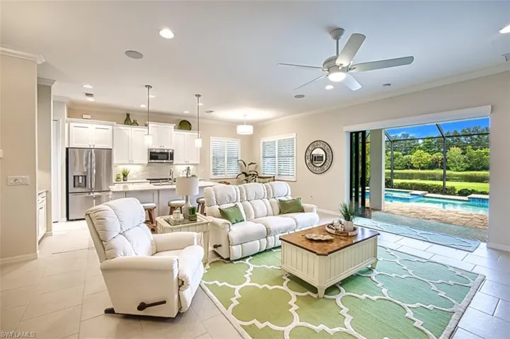 Tiled living room with a wealth of natural light, ceiling fan, and ornamental molding