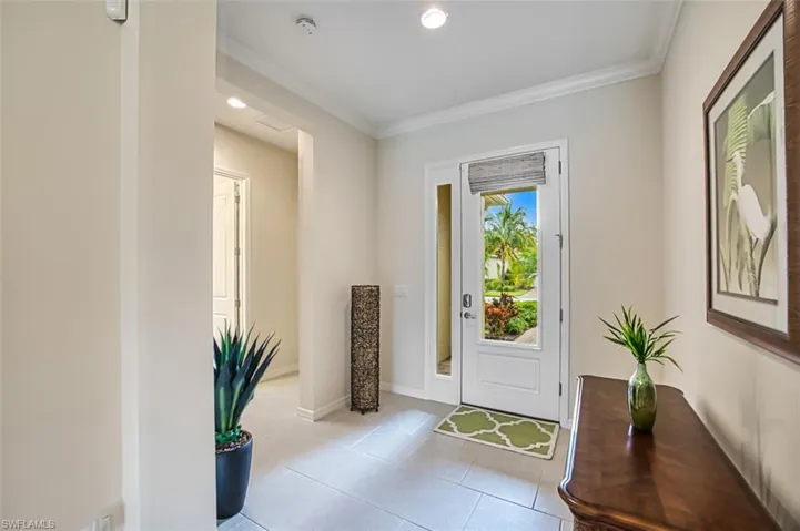 Doorway to outside with light tile patterned floors and ornamental molding