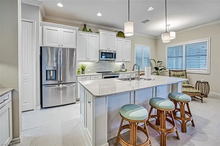 Kitchen featuring backsplash, white cabinets, sink, light tile patterned flooring, and stainless steel appliances