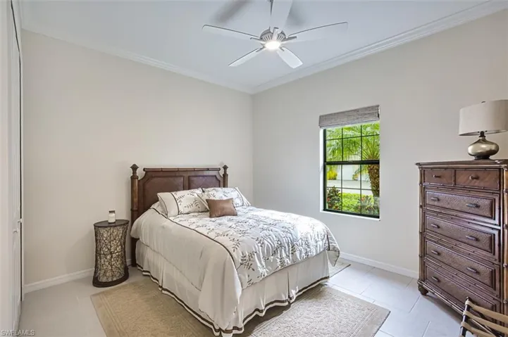 Tiled bedroom with ceiling fan and ornamental molding