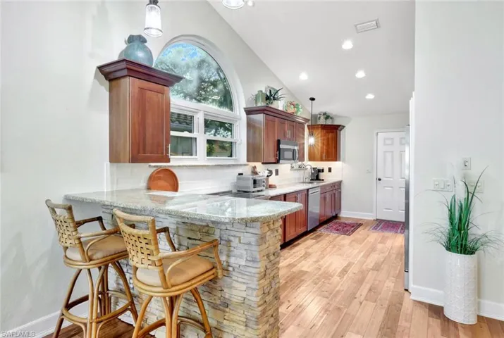 Kitchen featuring kitchen peninsula, pendant lighting, stainless steel appliances, and vaulted ceiling