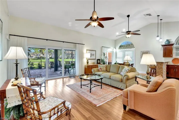 Living room with ceiling fan, plenty of natural light, lofted ceiling, and light hardwood / wood-style flooring