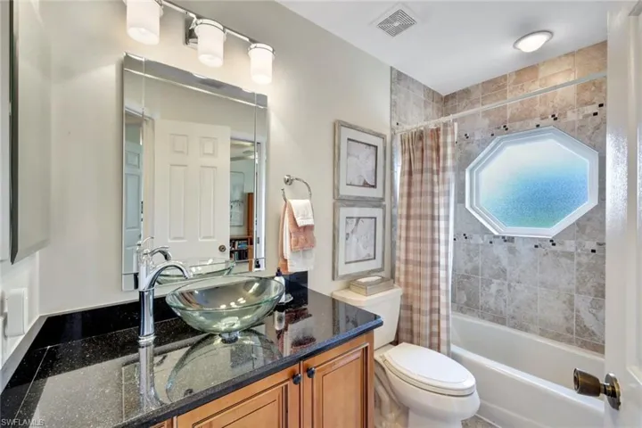 Full bathroom featuring vanity, shower / bathtub combination with curtain, and toilet