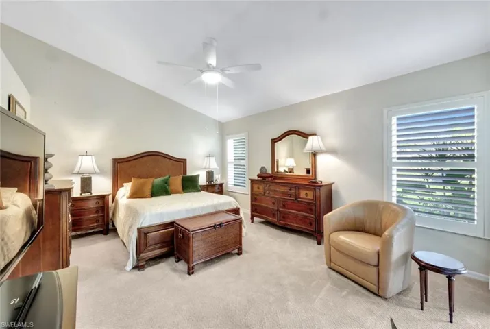 Carpeted bedroom with vaulted ceiling and ceiling fan