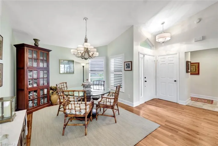 Dining area featuring light wood-type flooring, lofted ceiling, and an inviting chandelier