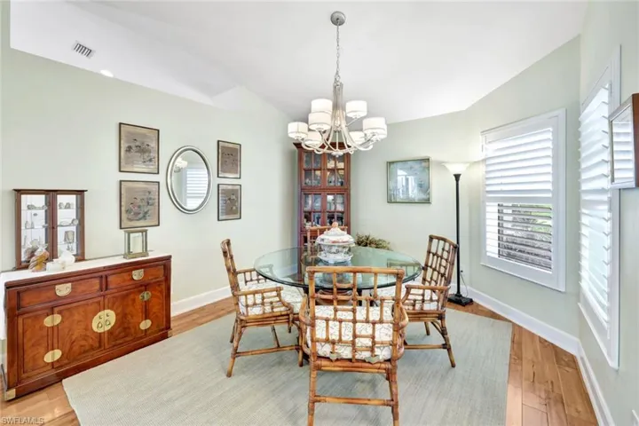 Dining area featuring a chandelier, vaulted ceiling, and light hardwood / wood-style flooring